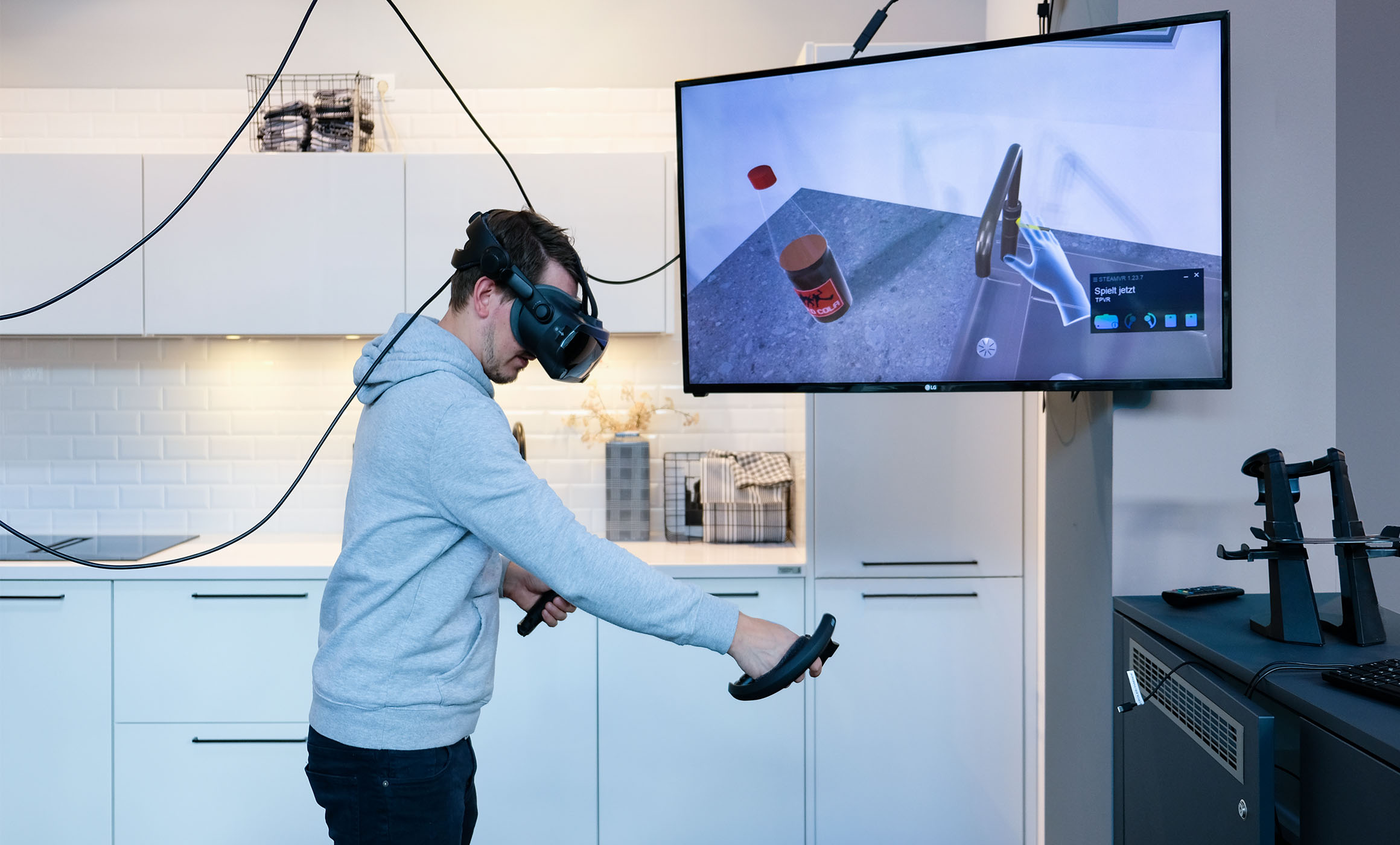 Im Hummel City Store ist es möglich die Küchenplanung mittels einer VR-Brille in 3D auf sich wirken zu lassen und die Dimension der neuen Küche zu erfahren. Zu sehen ist eine Person mit VR-Brille, die sich so im virtuellen Raum vor einer weißen Küche bewegt.